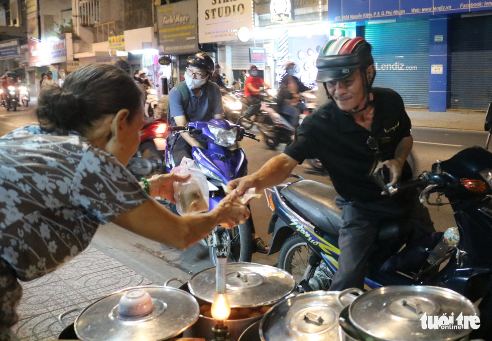 A customer buys Sau’s 'chè' (a Vietnamese sweet dessert) in a take-away container. Photo: Ngoc Phuong / Tuoi Tre