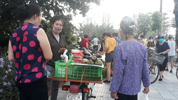 Two female buyers stand next to a seller whose goods are put on a motorbike. Photo: Tam Le / Tuoi Tre