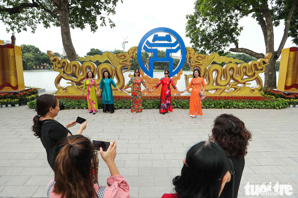 Hanoi residents pose in front of an ornament feature celebrating Hanoi’s 1010th anniversary in this photo taken at the Hoan Kiem Lake. Photo: Nguyen Khanh / Tuoi Tre