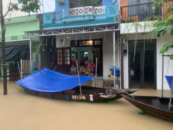 Residents on the southern bank of the Thu Bon River are seen behind a boat prepared for evacuation in this photo taken on Sunday. Photo: B.D. / Tuoi Tre