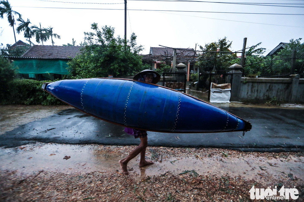 A man carries a boat on his shoulder on the way home before flooding in Thua Thien-Hue Province, October 16, 2020. Photo: Nguyen Khanh / Tuoi Tre
