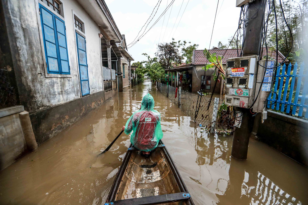 Local man Truong Dinh Cuong commutes on a boat in flooded Quang Phuoc Commune, Quang Dien District, Thua Thien-Hue Province on October 16, 2020. Photo: Nguyen Khanh / Tuoi Tre