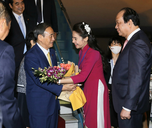 A Vietnamese woman gives flowers to Japanese Prime Minister Yoshihide Suga at Noi Bai International Airport in Hanoi, Vietnam, October 18, 2020. Photo: Vietnam News Agency