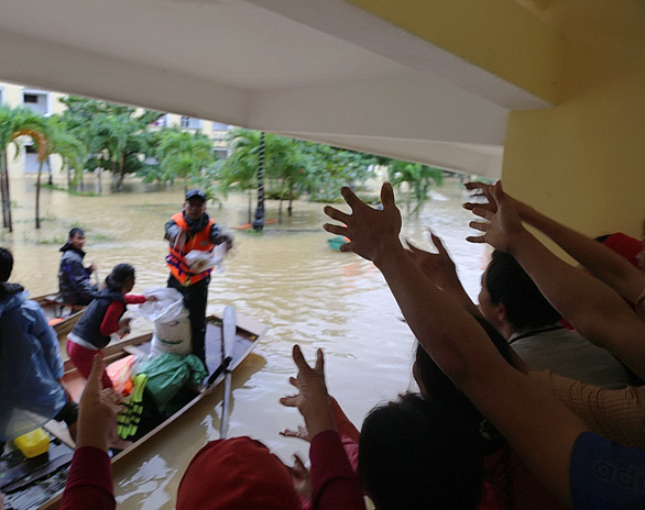 Stranded patients and caretakers at Le Thuy District’s General Hospital in Quang Binh Province reach out to catch aid packages from the rescue team. Photo: Minh Hoa / Tuoi Tre