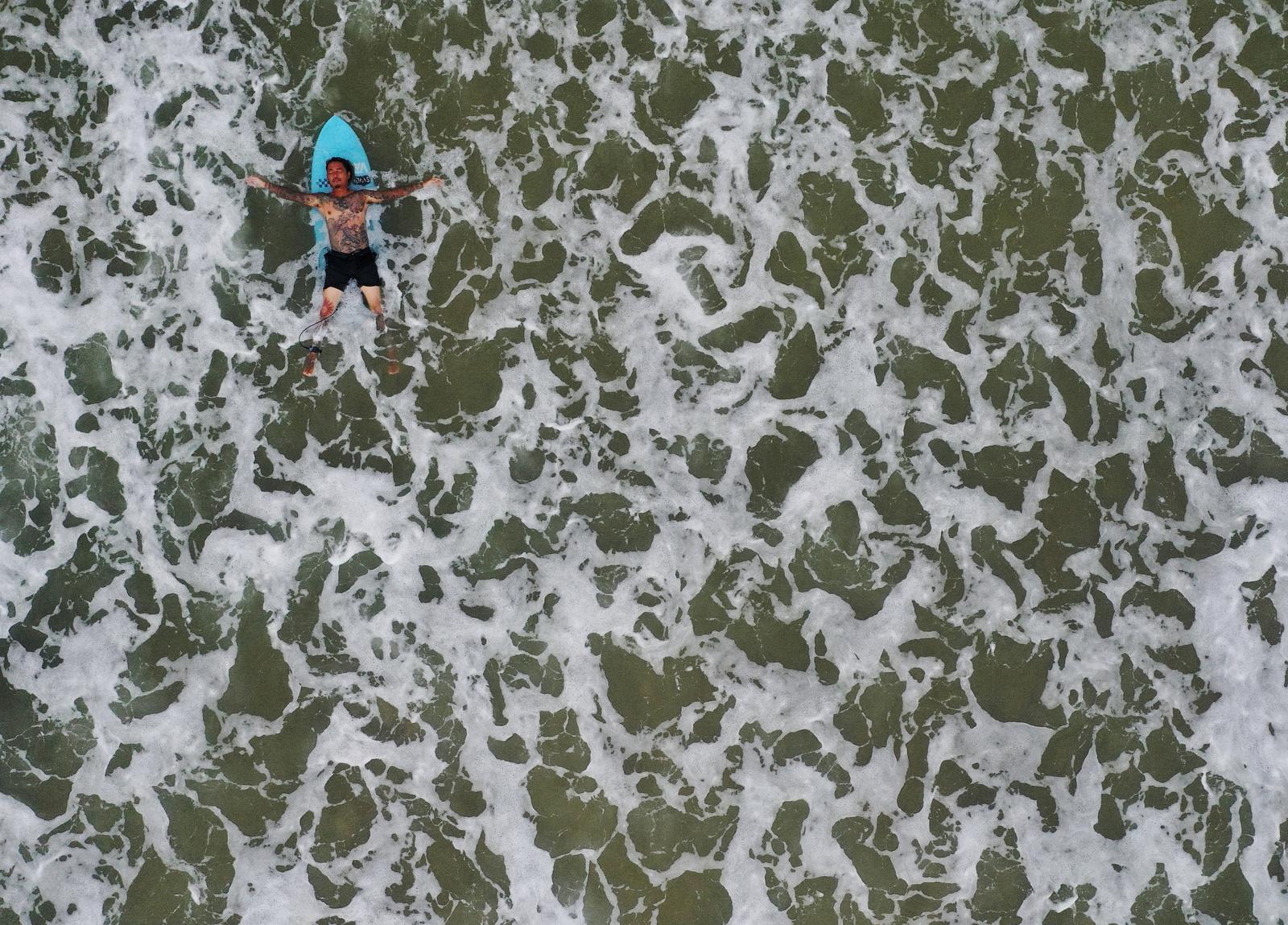 Surfer and TV set designer Takashi Mikajiri, 42, lies on his surfing board as he poses for a photo at Onjuku beach in Isumi district, Chiba Prefecture, Japan, October 4, 2020. Photo: Reuters