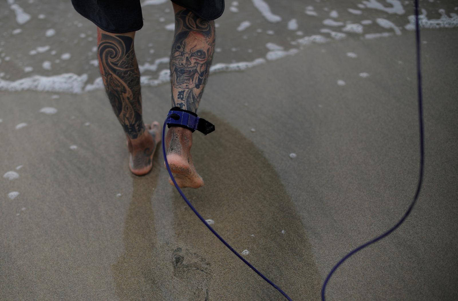 Surfer and TV set designer Takashi Mikajiri, 42, heads into the sea with his surfing board tied to his ankle at Onjuku beach in Isumi district, Chiba Prefecture, Japan, October 4, 2020. Photo: Reuters