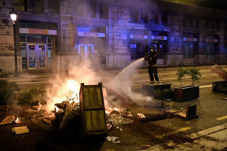 A firefighter douses burning trash after clashes erupted between members of the Catalan regional police force Mossos d'Esquadra and protesters during a demonstration against new coronavirus restrictions in Barcelona on October 30, 2020. Photo: AFP