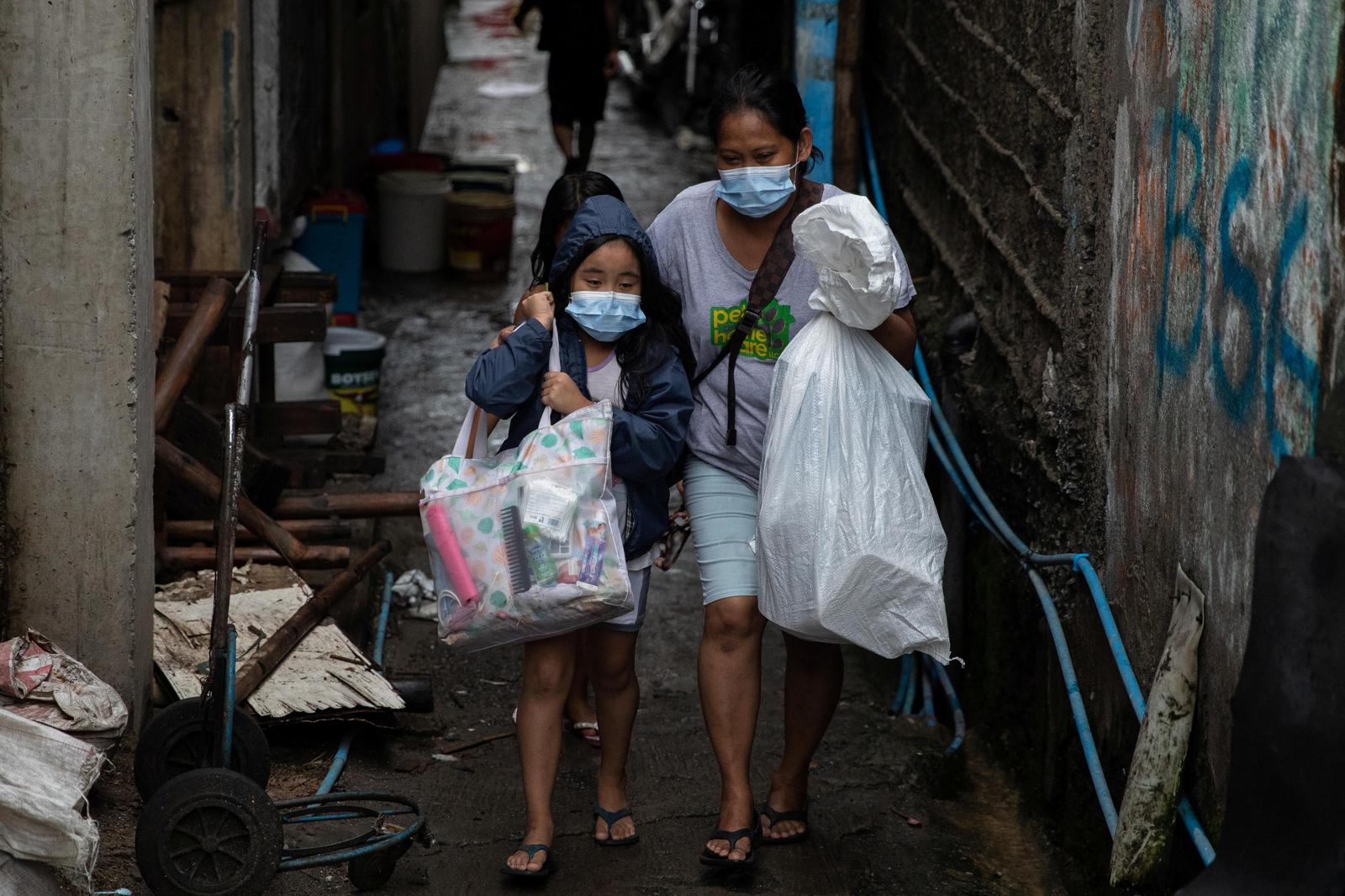 A woman and a child carry belongings as they evacuate from a coastal community ahead of Typhoon Vamco, in Sucat, Muntinlupa, Metro Manila, Philippines, November 11, 2020. Photo: Reuters
