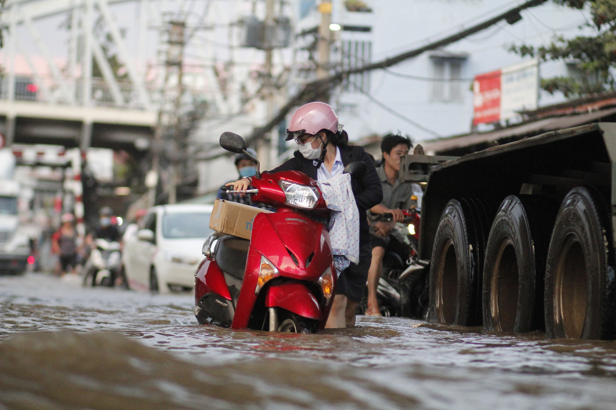 A woman pushes her broken-down motorbike on a flooded street in Ho Chi Minh City, November 16, 2020. Photo: Chau Tuan / Tuoi Tre