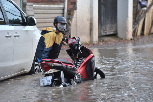A woman pushes her broken-down motorbike on a flooded street in Ho Chi Minh City, November 16, 2020. Photo: Duyen Phan / Tuoi Tre