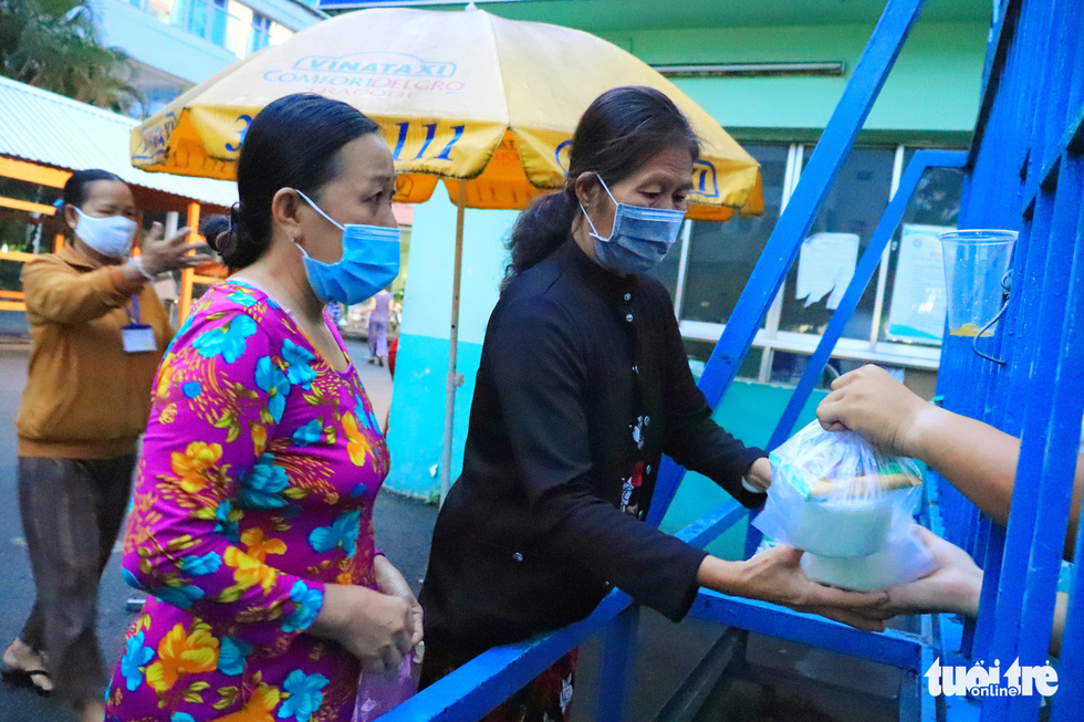 Patient caregivers at Ho Chi Minh City-based Pham Ngoc Thach Hospital, Vietnam receive free porridge portions through the hospital gate due to novel coronavirus (COVID-19) pandemic social distancing