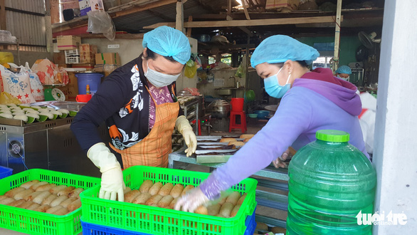 Two female workers deal with a batch of grilled bananas wrapped in sticky rice in the final stage of processing at Nguyen Thi Ngoc Bich’s company in Can Tho City, Vietnam.  Photo: Chi Hanh / Tuoi Tre