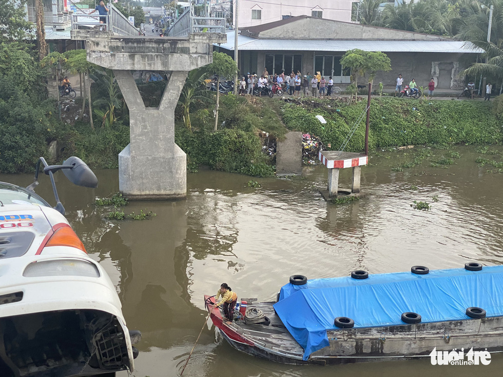 A boat is obstructed by a truck dangling from the remaining part of the Thien Ho Bridge on Nguyen Van Tiep canal after it collapsed due to the overweight truck in Cai Be District, Tien Giang Province, November 30, 2020. Photo: Hoai Thuong / Tuoi Tre