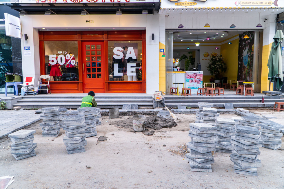 A construction worker installs natural stone paving on Nguyen Van Huyen Street of Hanoi. Photo: Pham Tuan / Tuoi Tre