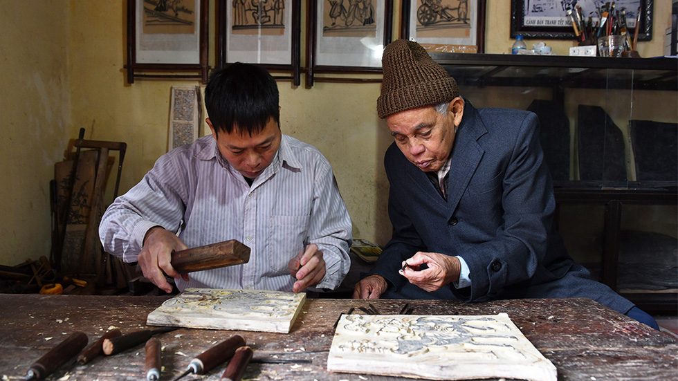 Nguyen Dang Che (right) and wood craftsman Nguyen Duc Tam (left) work on a wooden mold for Dong Ho painting. Photo: Hoang Ngoc Thach