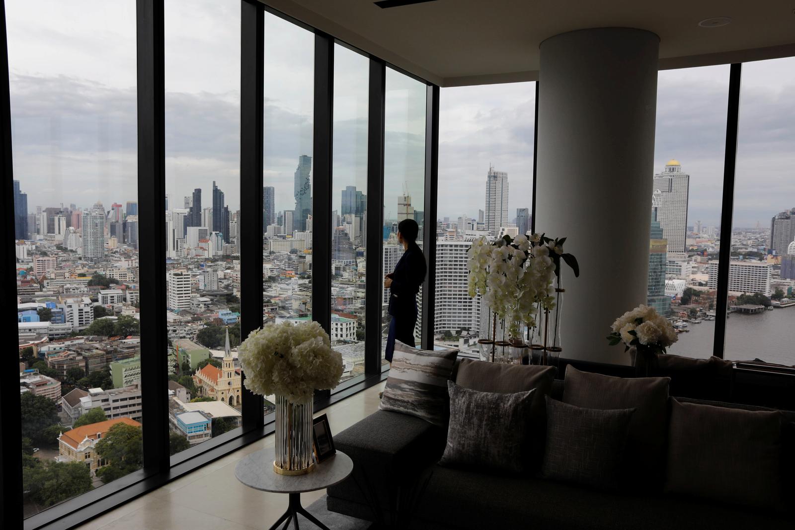 Lek, a saleswoman, looks through the window inside a luxury condo building next to the Chao Phraya river in Thon Buri, Bangkok, Thailand, August 23, 2019. Photo: Reuters