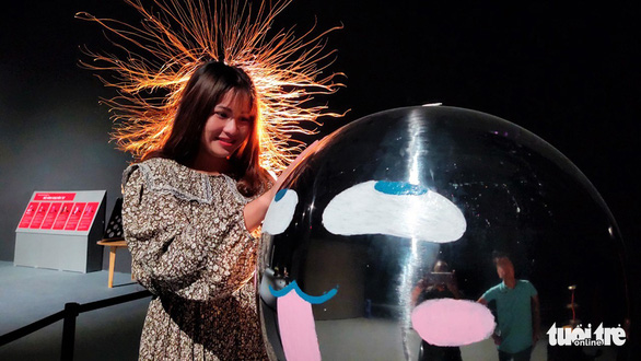 A female visitor enjoys an experience with electronic science. Her hairs ‘stands’ vertically after she touches her hand on a globe. Photo: Dung Nhan / Tuoi Tre