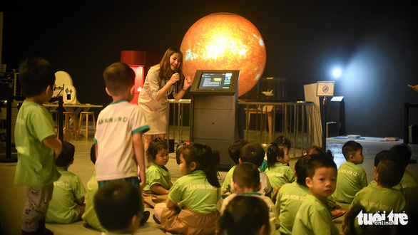 A staff from the Center for Scientific Discovery introduces a globe model containing planets in the solar system to a group children - Photo: Dung Nhan / Tuoi Tre