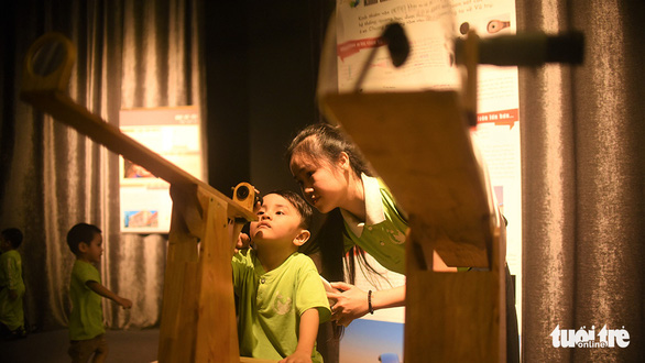 Two children look at a telescope in the Center for Scientific Discovery. Photo: Dung Nhan / Tuoi Tre