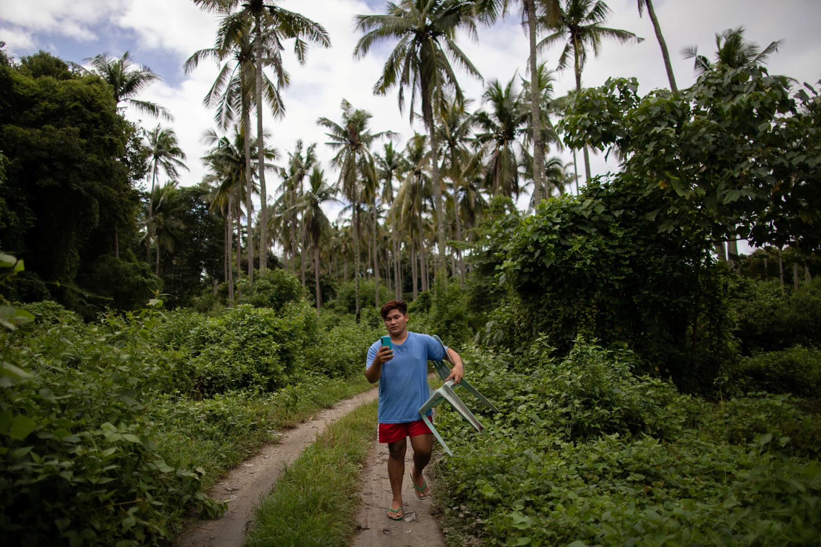 Mark Joseph Andal, 18, a college student, tries to find a spot in the forrest where there is an internet connection, in order to take part in an online class using his smartphone following the suspension of physical classes during the coronavirus disease (COVID-19) outbreak, in Mabalanoy, San Juan, Batangas, Philippines October 15, 2020. Andal has taken a part-time job in construction to purchase a smartphone for virtual classes and has also built a forest shelter to capture an internet signal. When the signal fades, Andal picks up his plastic chair to move to another spot, and if it rains, he holds the phone in one hand and an umbrella in the other. 'We're not rich, and finishing school is my only way to repay my parents for raising me.' Photo: Reuters