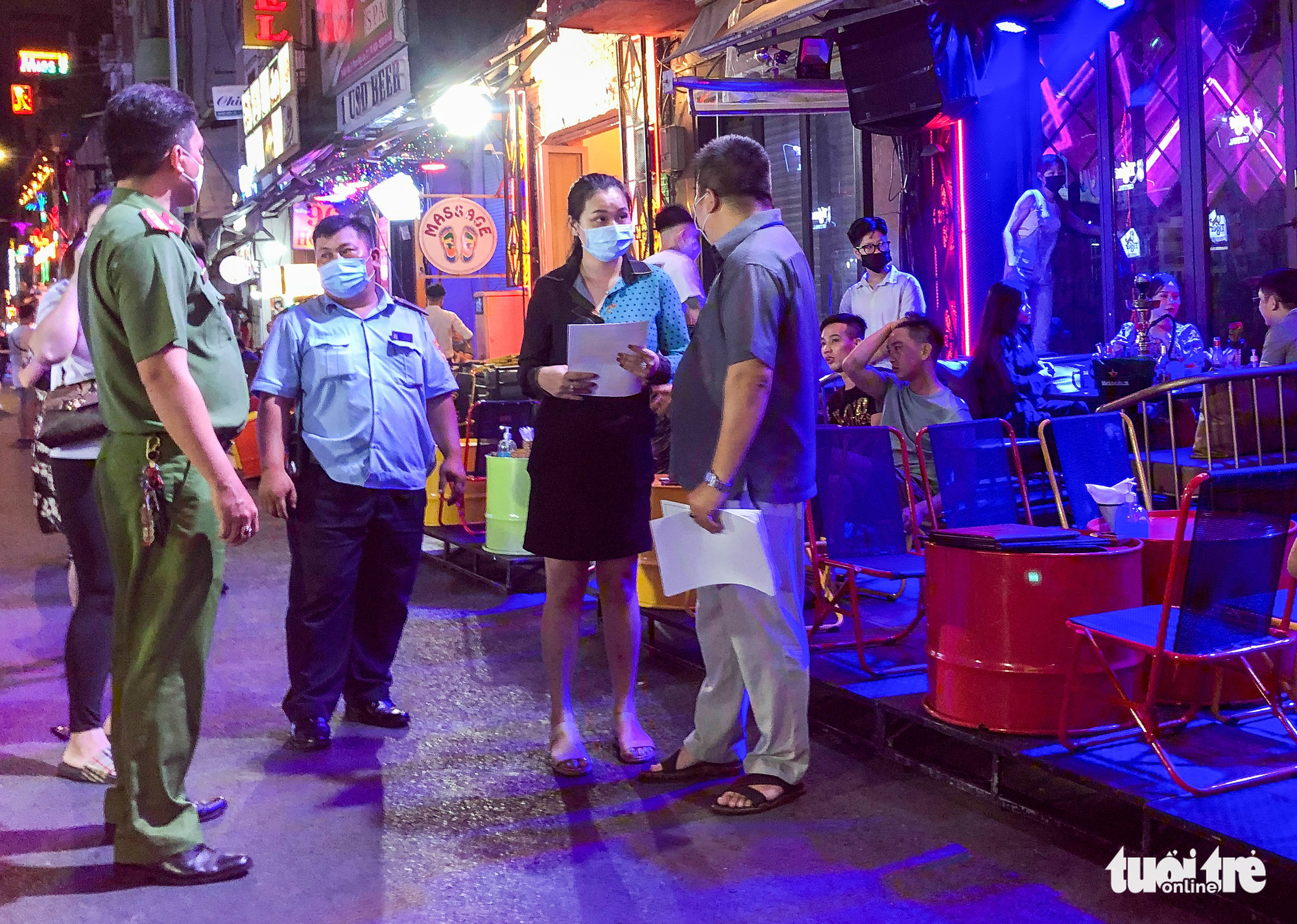 An official explains to a store owner the terms of a noise-reducing commitment during an inspection of businesses on Bui Vien Street in Ho Chi Minh City, Vietnam, March 20, 2021. Photo: Chau Tuan / Tuoi Tre