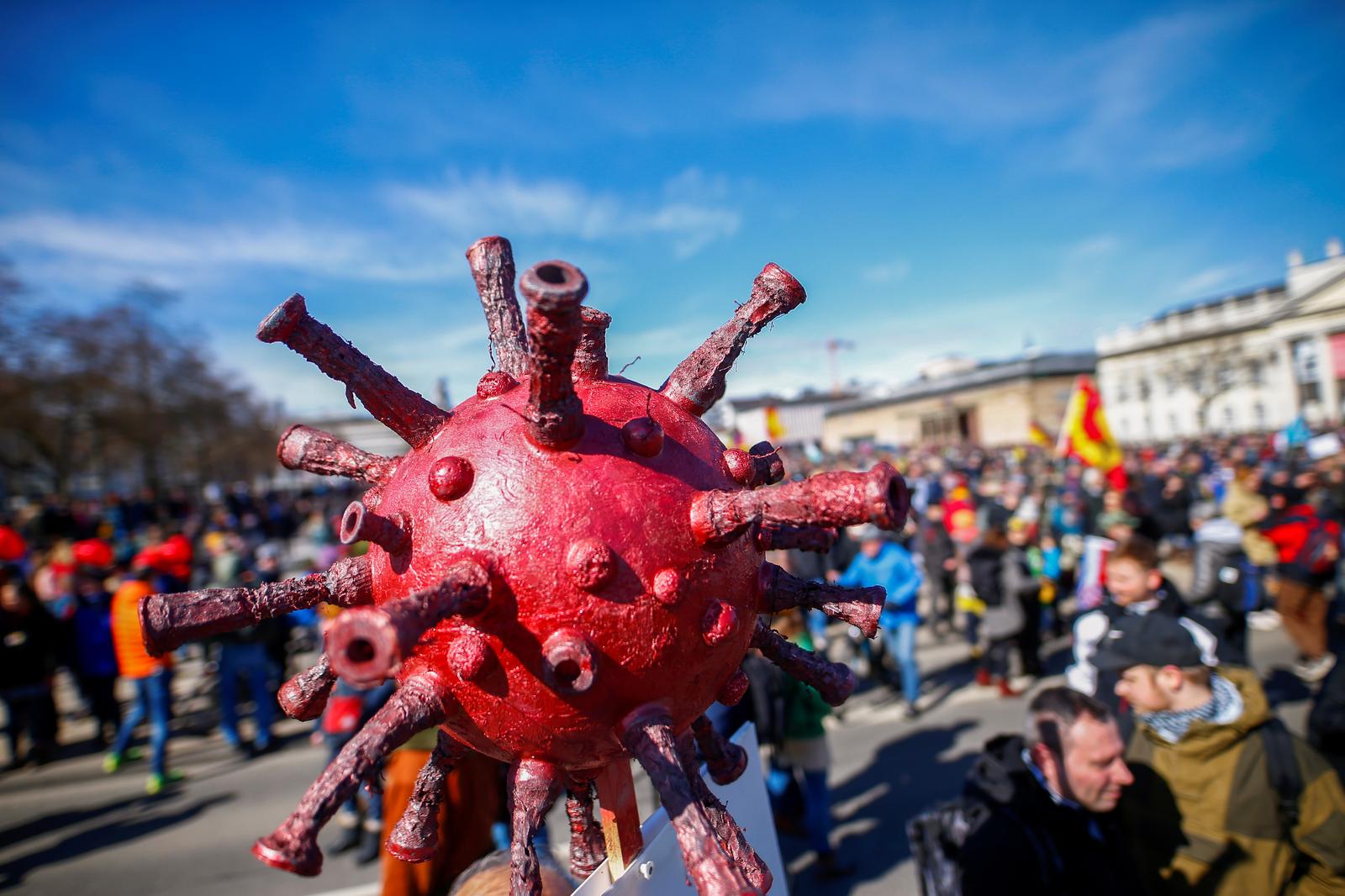 A model of the coronavirus is seen attached to a sign during a protest against the government's coronavirus disease (COVID-19) restrictions in Kassel, Germany March 20, 2021. Photo: Reuters