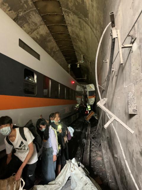 People walk next to a train which derailed in a tunnel north of Hualien, Taiwan April 2, 2021, in this handout image provided by Taiwan's National Fire Agency. Photo: Taiwan's National Fire Agency/Handout via Reuters