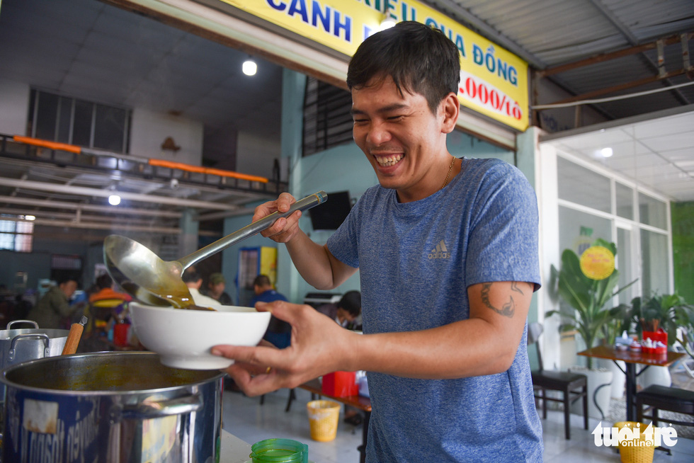 Nguyen Dang Hoang Minh, Mai’s husband, helps her sell crab paste vermicelli soup. Photo: Ngoc Phuong / Tuoi Tre