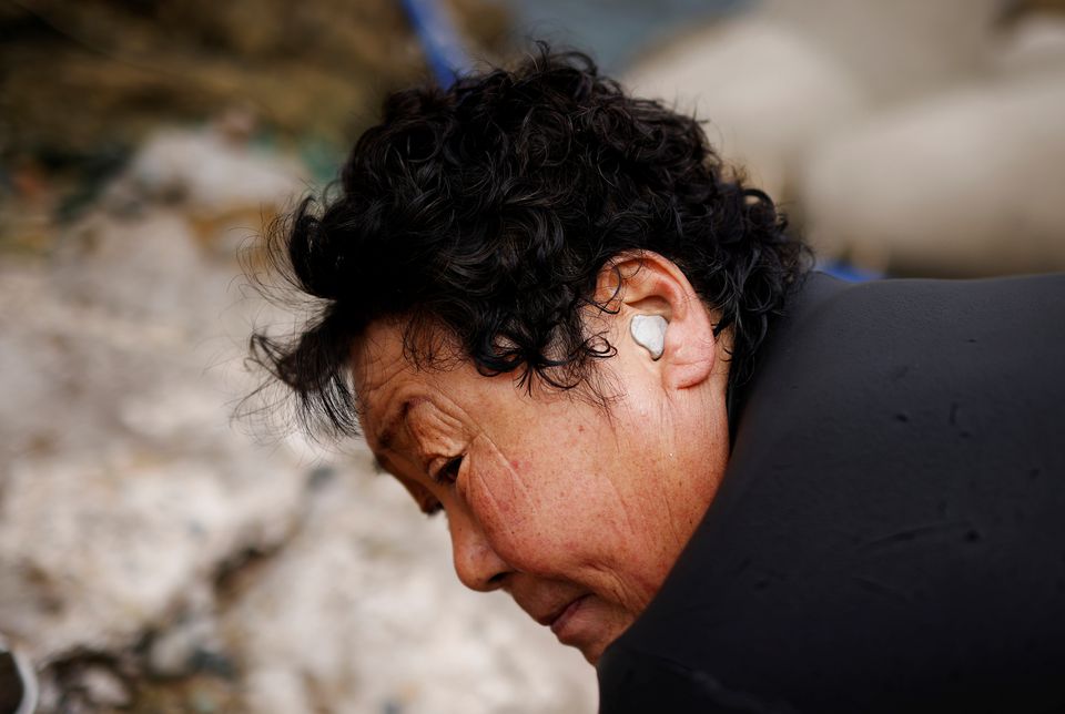Ko Seung-yo, 72, a senior haenyeo, also known as a 'sea woman', wears rubber clay in her ears as she walks back to the port after working in the sea in Busan, South Korea, April 6, 2021. Photo: Reuters