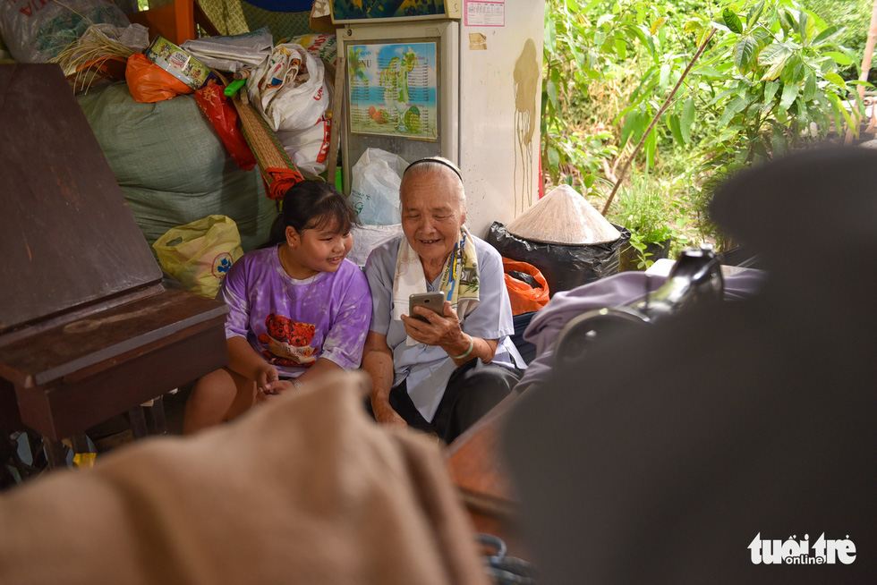 Grandma Tu takes a break watching a video with her granddaughter. – Photo: Ngoc Phuong/Tuoi Tre