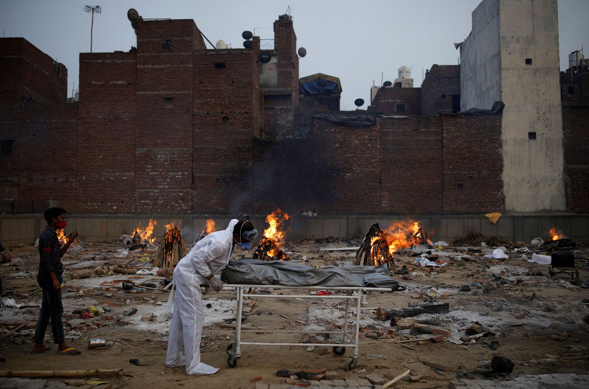 A man wearing personal protective equipment (PPE) carries a body of a relative, who died from the coronavirus disease (COVID-19), for his cremation, at a crematorium in New Delhi, India May 5, 2021. Photo: Reuters