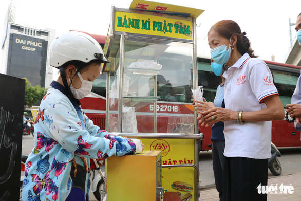A child donates money after receiving a free sandwhich. Photo: Hoang An / Tuoi Tre
