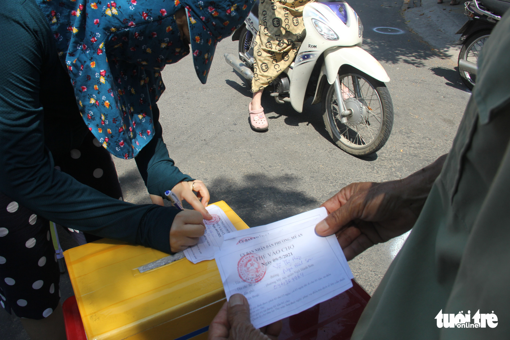 A resident fills in personal information on an ‘admission ticket’ before entering a market in Da Nang City, Vietnam, May 9, 2021. Photo: Truong Trung / Tuoi Tre