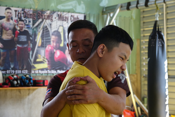 Nguyen Tri Dung’s father helps to deal with ligament pain in his right arm. Photo: Hoang Tung / Tuoi Tre