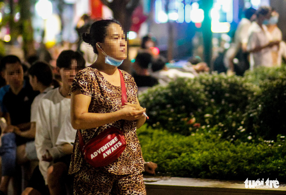 A woman is walking and smoking without wearing facemask at a public area in Ho Chi Minh City. Photo: Chau Tuan / Tuoi Tre
