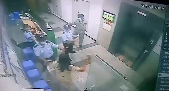 A woman is about to attack a security guard with a slipper at an apartment building in this screenshot taken from CCTV footage.