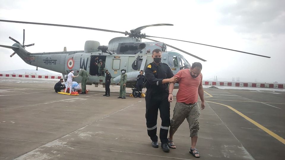 A member of the Indian Navy helps a man to walk after he was rescued by Indian Navy personnel from a sunken barge in the Arabian Sea after cyclone Tauktae's landfall, at naval air station INS Shikra in Mumbai, May 18, 2021. Indian Navy/Handout via Reuters
