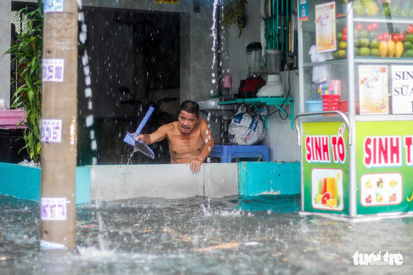 A resident street in Thu Duc City, Ho Chi Minh City, Vietnam scoops floodwater out of his house. Photo: Chau Tuan / Tuoi Tre