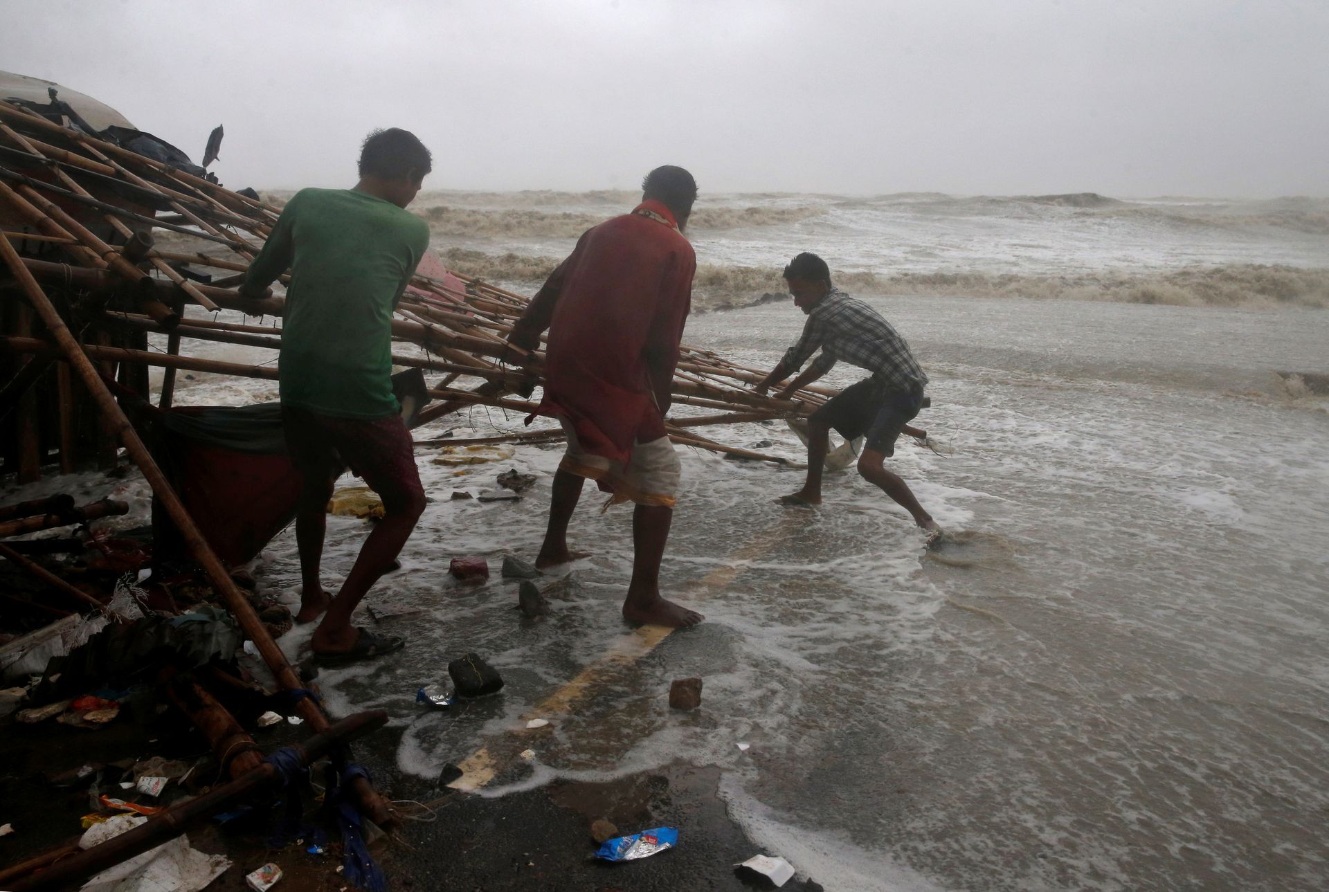 Men remove bamboo rooftop of a stall damaged by heavy winds at a shore ahead of Cyclone Yaas in Bichitrapur in Balasore district in the eastern state of Odisha India, May 26, 2021. Photo: Reuters