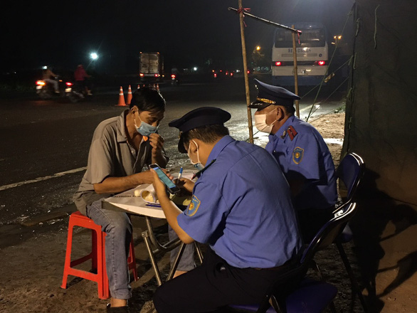 Officers at a COVID-19 checkpoint in Ho Chi Minh City book a bus operator for violations of coronavirus prevention guidelines. Photo: Minh Thanh / Tuoi Tre