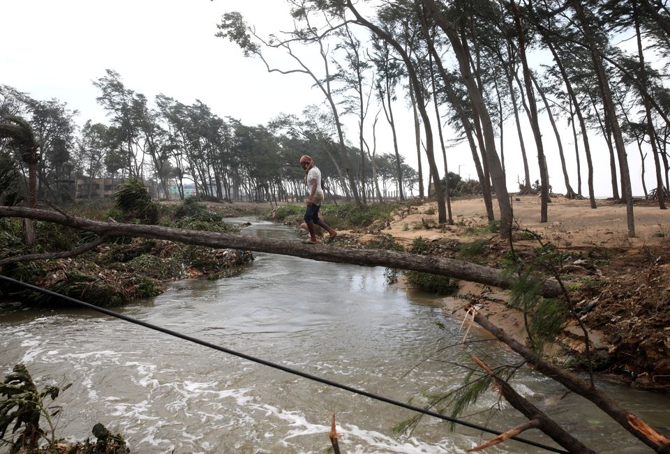 A man crosses a canal on a fallen tree following Cyclone Yaas in Digha, Purba Medinipur district in the eastern state of West Bengal, India, May 27, 2021. Photo: Reuters