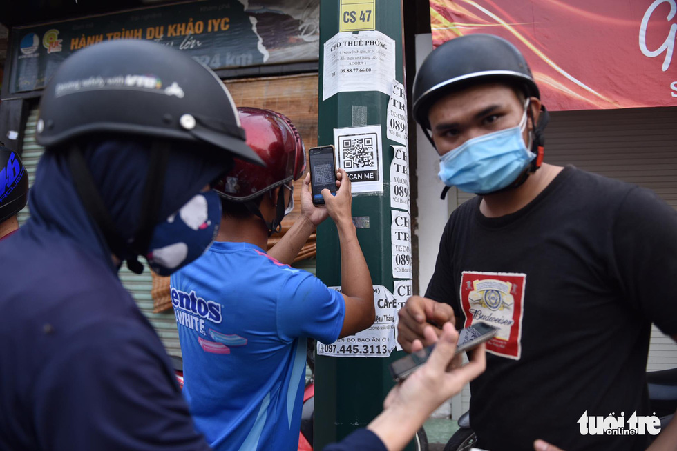 A commuter scans a QR code to perform a health declaration on a mobile phone as required to be allowed to pass a COVID-19 checkpoint in Go Vap District, Ho Chi Minh City, June 1, 2021. Photo: Ngoc Phuong / Tuoi Tre