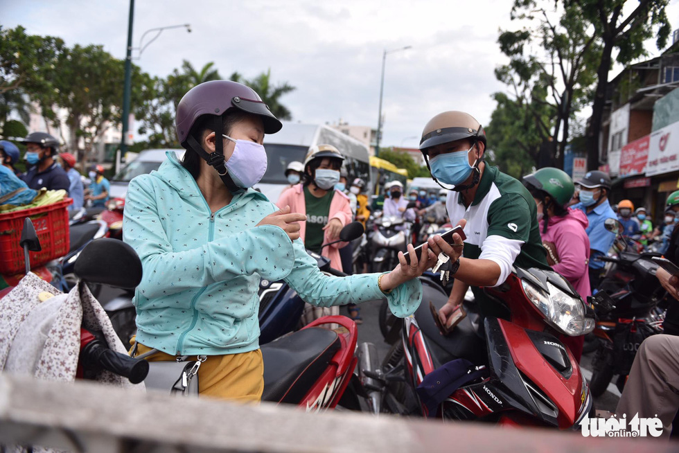 A woman helps a man perform a health declaration on his mobile phone as required to be allowed to pass a COVID-19 checkpoint in Go Vap District, Ho Chi Minh City, June 1, 2021. Photo: Ngoc Phuong / Tuoi Tre