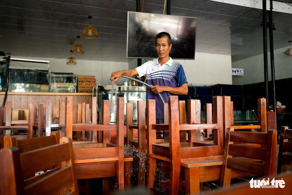 A restaurant owner disinfects tables and chairs to prepare for the reoperation in Da Nang City, Vietnam. Photo: Tan Luc / Tuoi Tre