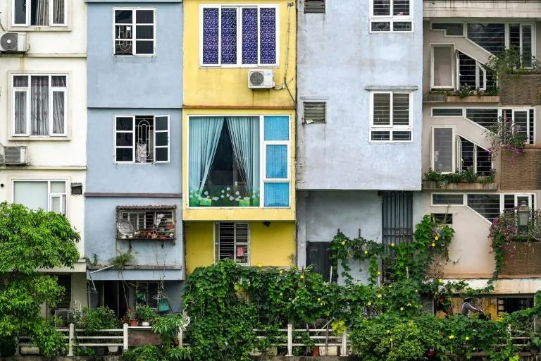 This photograph taken on June 8, 2021 shows a street vendor walking past narrow residential houses, known as 'nha ong' in Vietnamese or 'tube houses', in an urban area of Hanoi. Photo: AFP