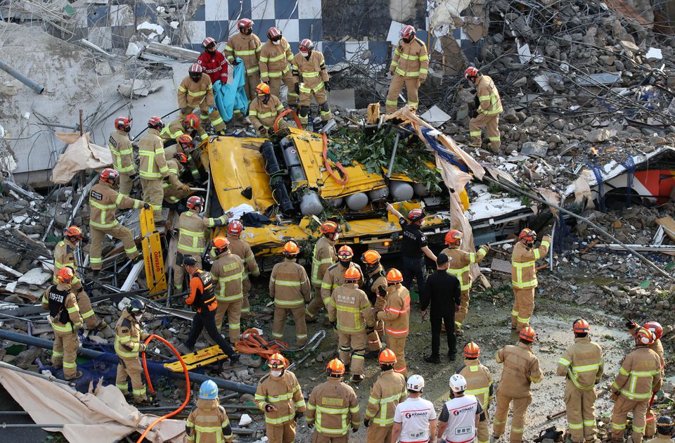 South Korean firefighters search for passengers from a bus trapped by the debris of a collapsed building in Gwangju, South Korea, June 9, 2021. Yonhap via Reuters