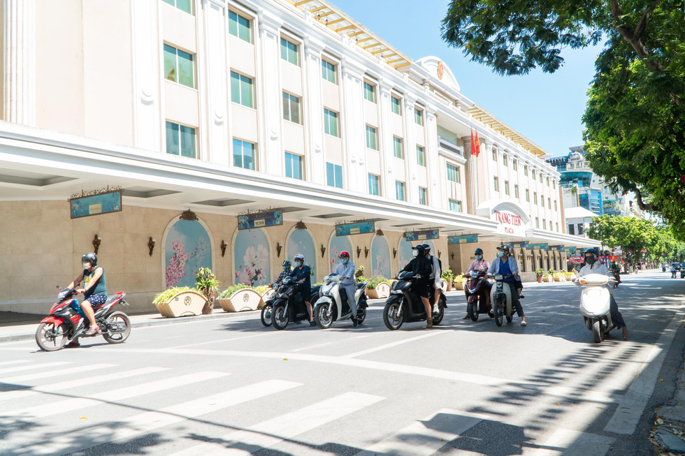 Motorcyclists stop their vehicles under the tree shadow to avoid the scorching temperature of over 50 degrees Celsius on a street in Hanoi, June 20, 2021. Photo: Pham Tuan / Tuoi Tre