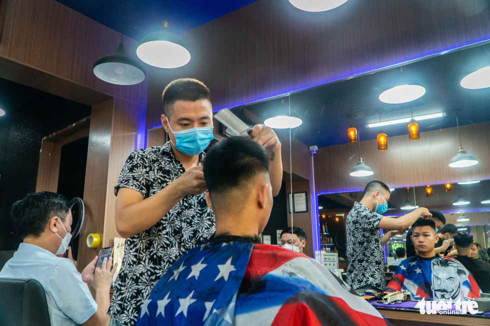 Anh Thai, owner of a barbershop in Hanoi, serves a customer in the reopening day of his shop, June 22, 2021. Photo: Pham Tuan / Tuoi Tre