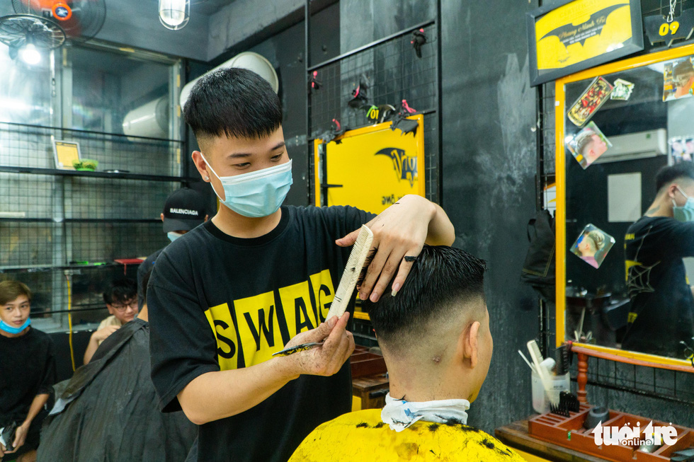 A customer gets his hair trimmed in a barbershop in Hanoi, June 22, 2021. Photo: Pham Tuan / Tuoi Tre