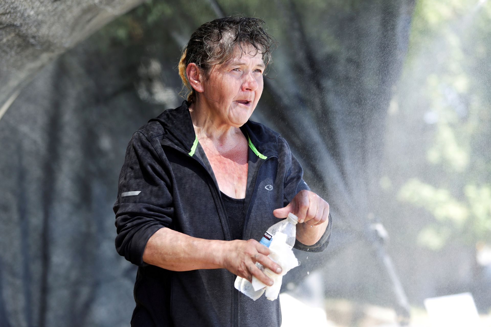 Katherine Milton, originally of Juneau, Alaska, who is experiencing homelessness, cools off under a homemade cooling-off station and mist system that a neighbor set up in their front yard for people, especially those without homes, during the scorching weather in Seattle, Washington, June 28. Photo: Reuters